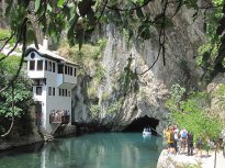 31 Vývěr Buny u Blagaje - řeka vytéká z jeskyně pod vysokou skálou.